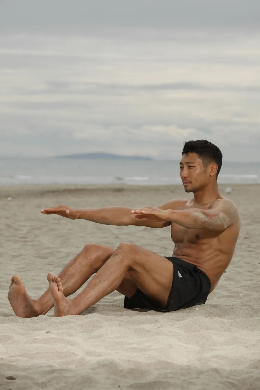 A man doing a bodyweight workout on a sandy beach