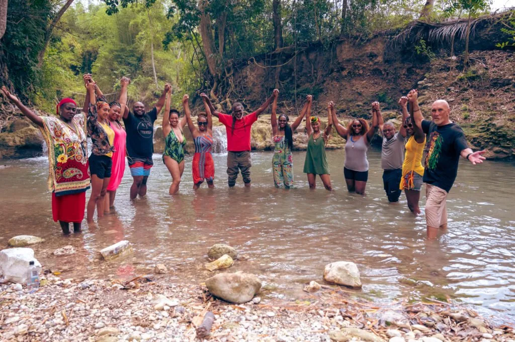 Guests and hosts standing together in the river at Rastafari Indigenous Village
