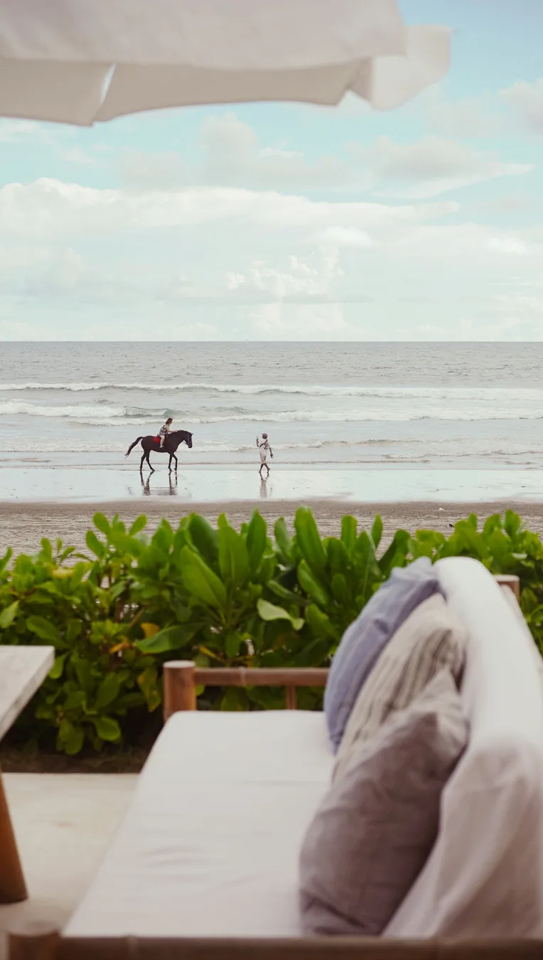 A horseback rider moving along a wide sandy beach