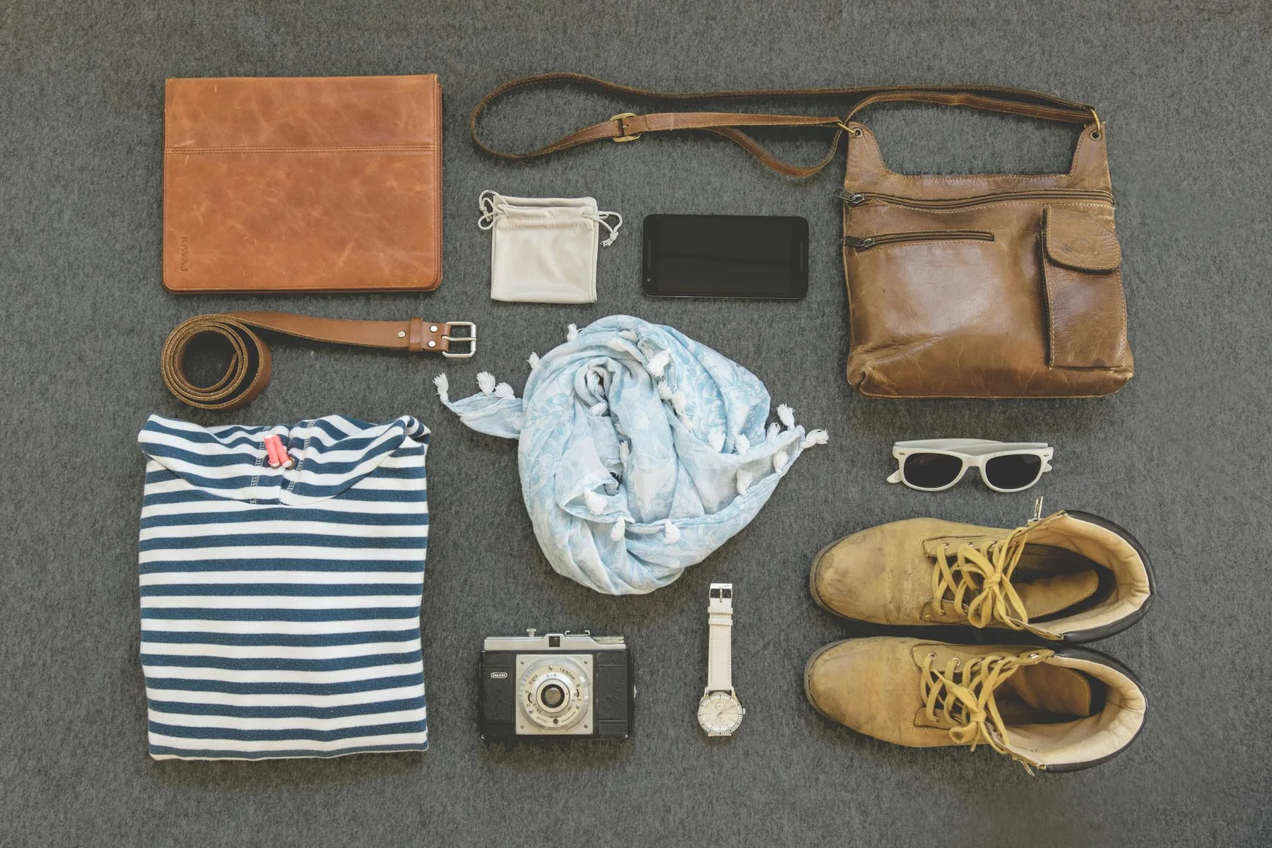Travel clothes, walking shoes, sunglasses and a bag laid out before packing