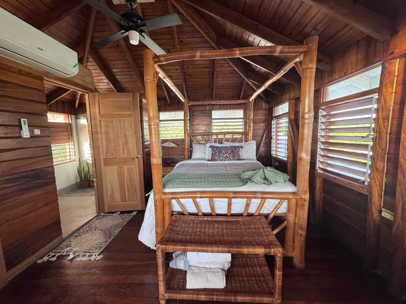 Four-poster bed and warm timber interior — The Doctor Bird, Coral Cove Wellness Resort